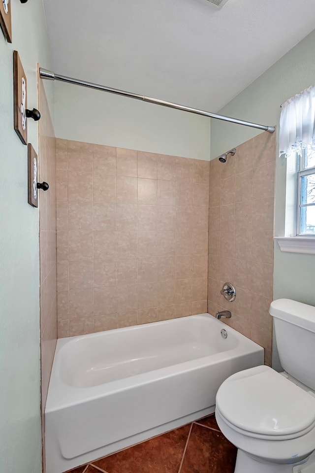 bathroom with toilet, tiled shower / bath combo, and tile patterned flooring