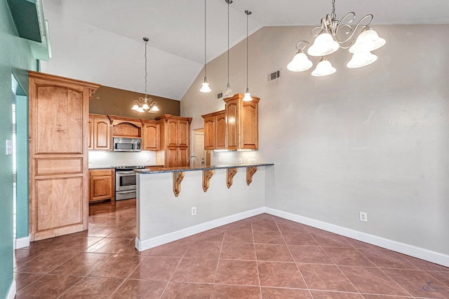 kitchen with hanging light fixtures, appliances with stainless steel finishes, a breakfast bar, and a notable chandelier