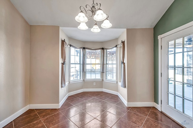 unfurnished dining area with a notable chandelier and dark tile patterned floors