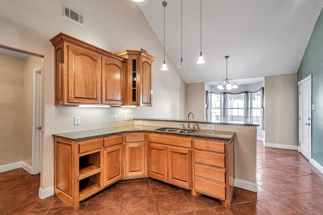 kitchen featuring sink, dark tile patterned floors, stone counters, hanging light fixtures, and vaulted ceiling