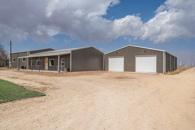 view of front of home featuring a garage, an outbuilding, and central AC