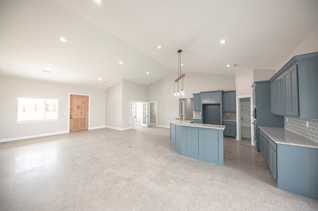 kitchen featuring pendant lighting, a kitchen island with sink, high vaulted ceiling, sink, and tasteful backsplash