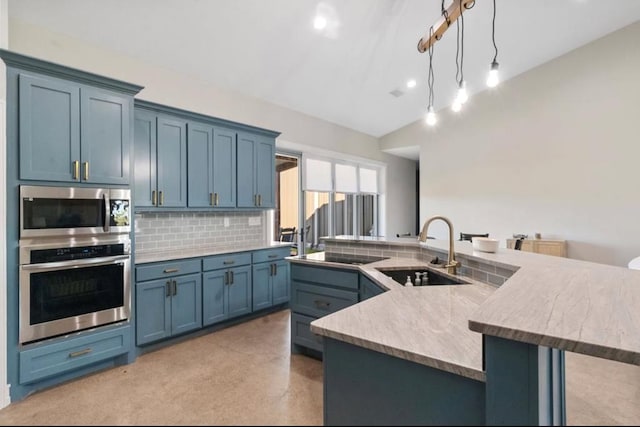 kitchen with lofted ceiling, backsplash, a large island with sink, sink, and stainless steel appliances