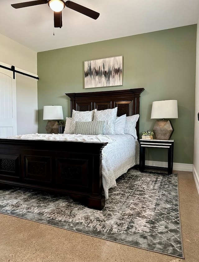 carpeted bedroom featuring a barn door and ceiling fan