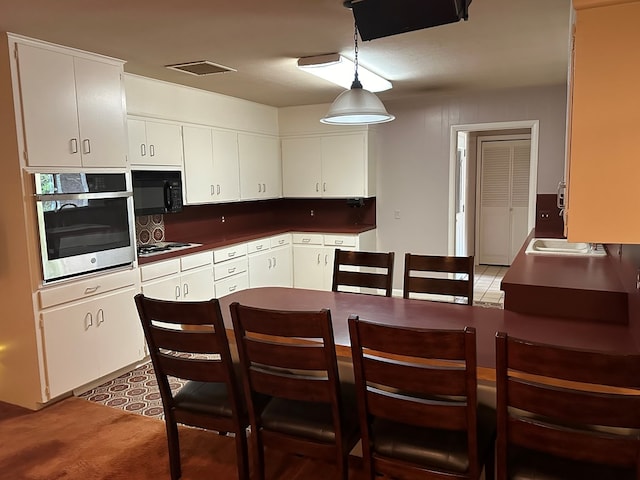 kitchen featuring stainless steel oven, white cabinetry, hanging light fixtures, and white gas stovetop