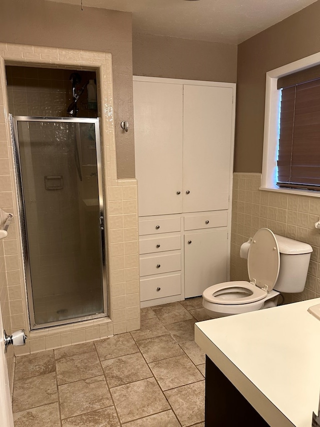 bathroom featuring walk in shower, vanity, toilet, and tile walls