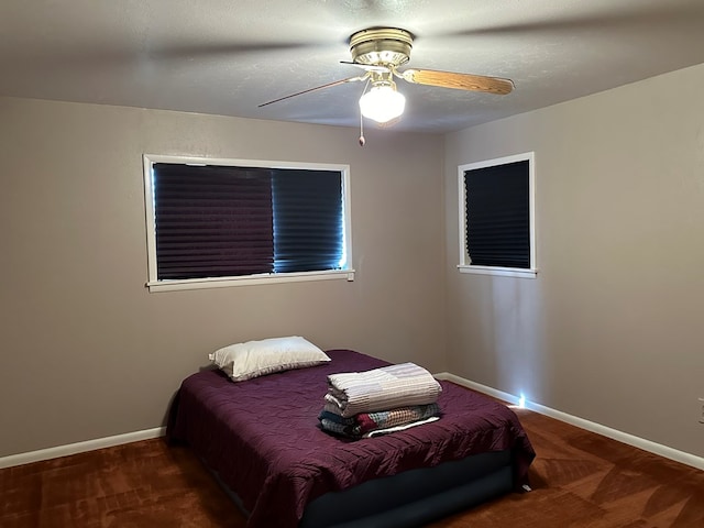 bedroom with a textured ceiling, dark carpet, and ceiling fan