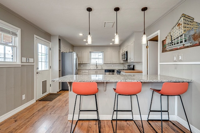 2607 N N St, Midland, TX 79705 - kitchen with a sink, light wood finished floors, a peninsula, ornamental molding, and stainless steel appliances