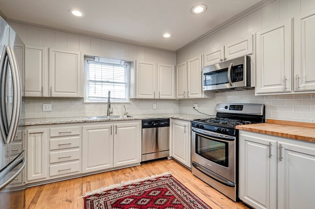 2607 N N St, Midland, TX 79705 - kitchen featuring ornamental molding, white cabinets, tasteful backsplash, a sink, and stainless steel appliances