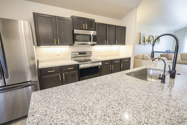 2908 Stagecoach Ct, Midland, TX 79705 - kitchen featuring appliances with stainless steel finishes, light stone countertops, open floor plan, and dark brown cabinets