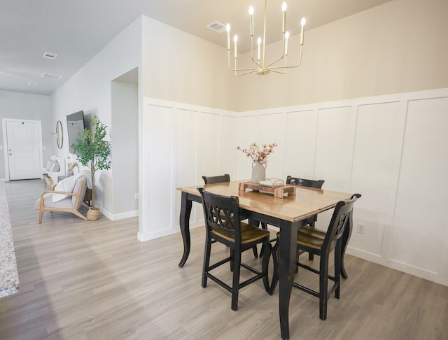2908 Stagecoach Ct, Midland, TX 79705 - dining room featuring a decorative wall, a chandelier, light wood-type flooring, and a wainscoted wall