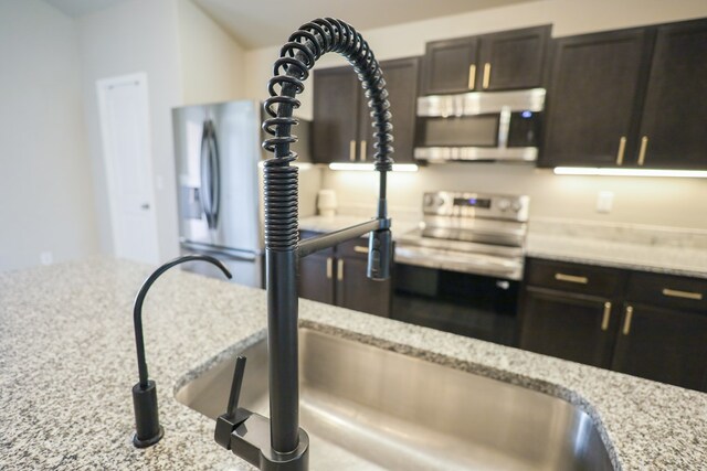 2908 Stagecoach Ct, Midland, TX 79705 - kitchen featuring appliances with stainless steel finishes, light stone countertops, and dark brown cabinets