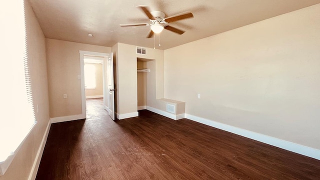 unfurnished bedroom featuring ceiling fan, multiple windows, dark wood-type flooring, and a closet