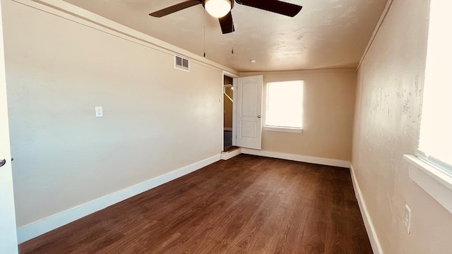 empty room featuring ceiling fan, dark wood-type flooring, and ornamental molding