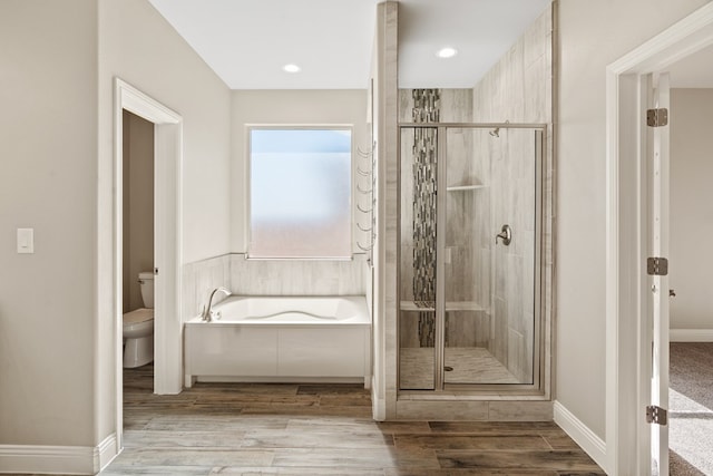 bathroom featuring toilet, hardwood / wood-style flooring, and plus walk in shower