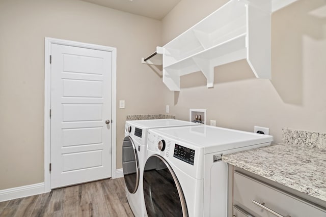 laundry room featuring separate washer and dryer, cabinets, and light hardwood / wood-style flooring