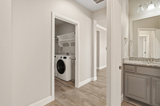 laundry area with sink, light hardwood / wood-style floors, and washer / clothes dryer