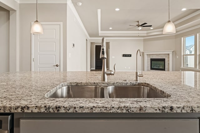 kitchen with sink, hanging light fixtures, ceiling fan, and a tray ceiling