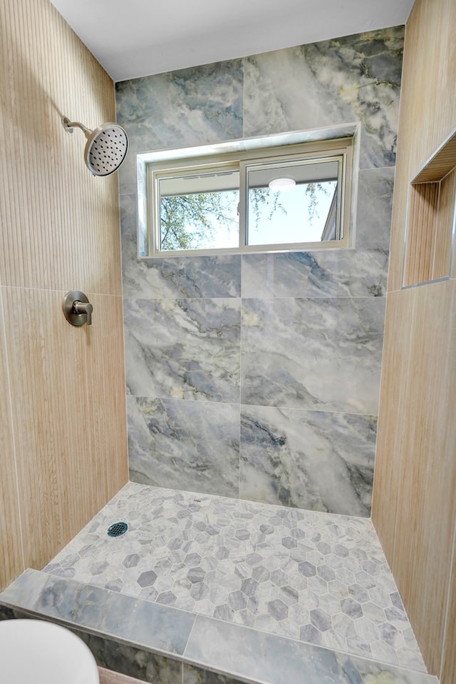 bathroom with toilet and a tile shower