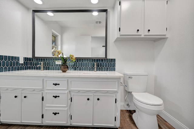 bathroom featuring hardwood / wood-style floors, decorative backsplash, toilet, and vanity