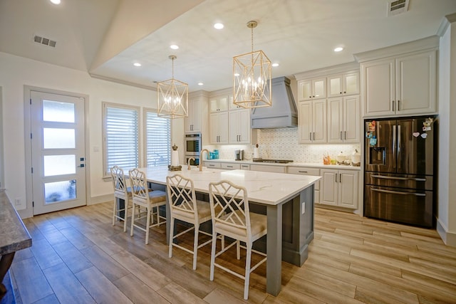 kitchen featuring light stone countertops, a large island, hanging light fixtures, appliances with stainless steel finishes, and custom exhaust hood