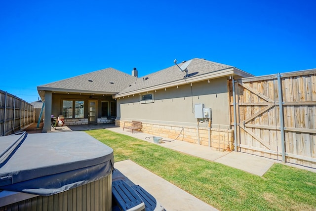 back of property featuring a hot tub and a patio area