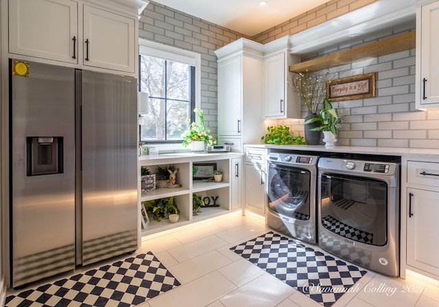 laundry area with cabinets, light tile patterned floors, and washer and clothes dryer