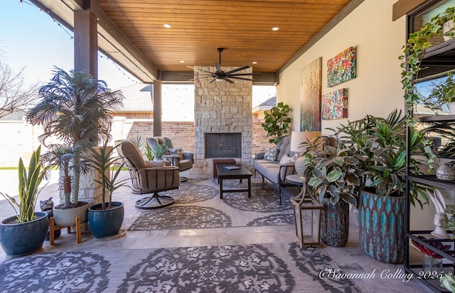 view of patio / terrace with ceiling fan and an outdoor living space with a fireplace