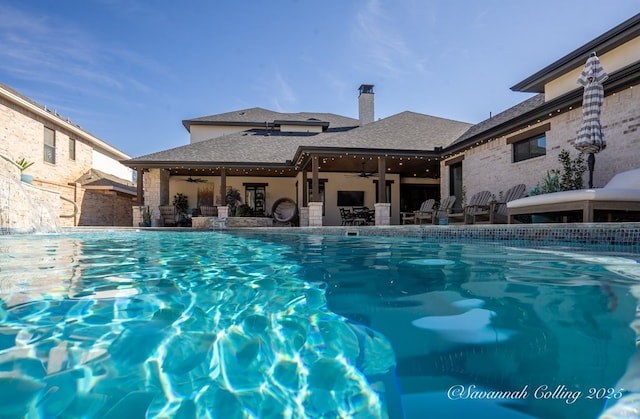 view of swimming pool featuring pool water feature and ceiling fan