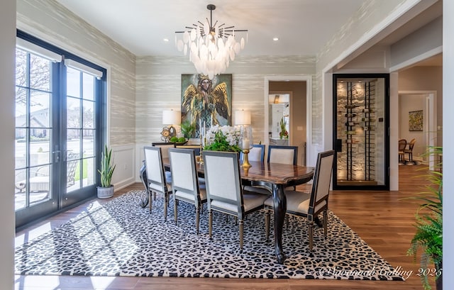 dining room featuring an inviting chandelier, wood-type flooring, ornamental molding, and french doors