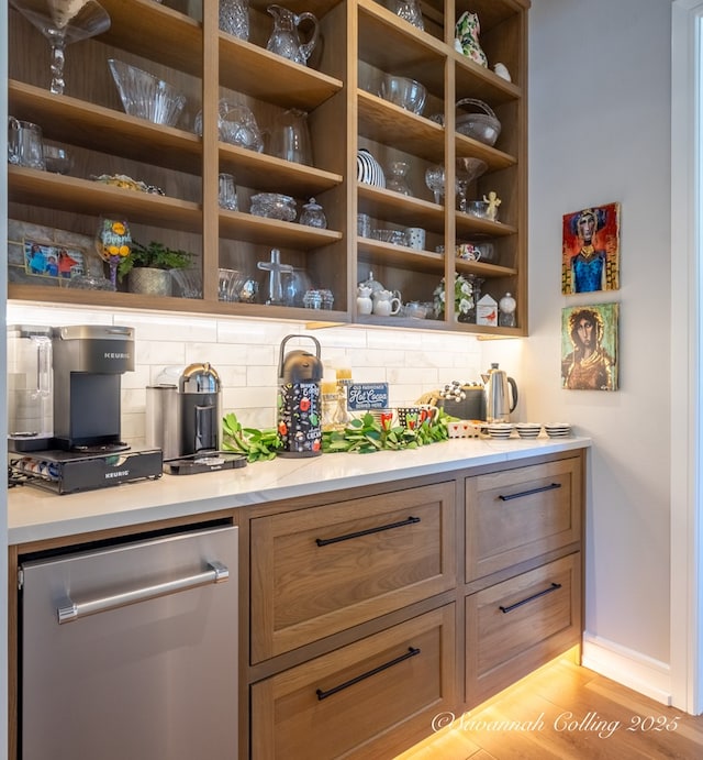 bar featuring stainless steel dishwasher, light hardwood / wood-style floors, and decorative backsplash