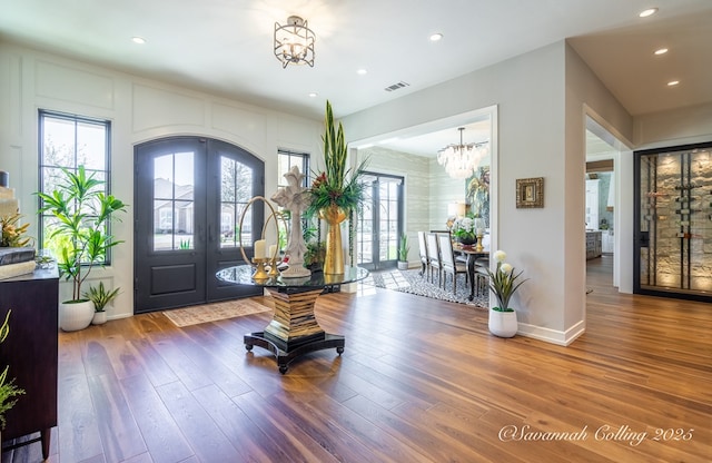 foyer entrance featuring french doors, a chandelier, and hardwood / wood-style floors