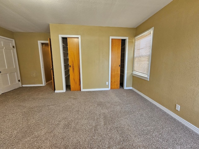 unfurnished bedroom with carpet flooring, a walk in closet, a closet, and a textured ceiling