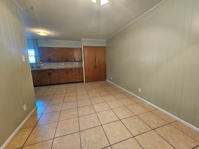 interior space with wooden walls, light tile patterned flooring, and a textured ceiling