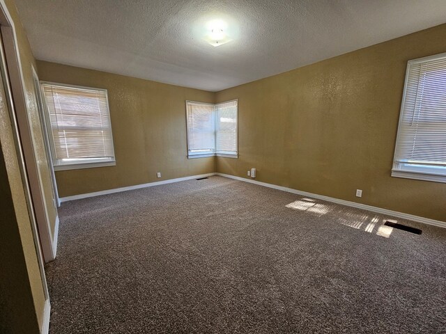 carpeted spare room with a textured ceiling