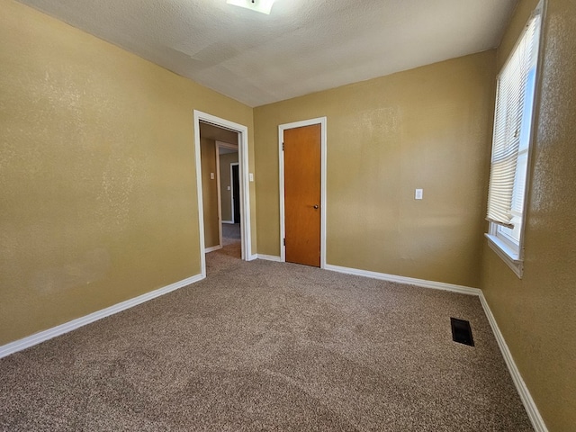 carpeted empty room with a textured ceiling