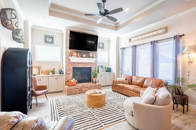 living room with ceiling fan, light hardwood / wood-style floors, crown molding, and a brick fireplace