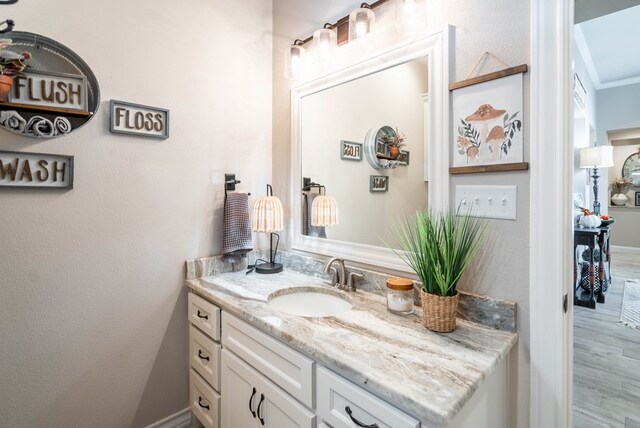 bathroom with hardwood / wood-style floors, vanity, and ornamental molding