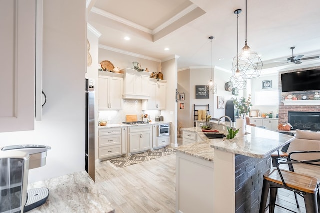 kitchen with white cabinets, ceiling fan, light stone counters, and a breakfast bar