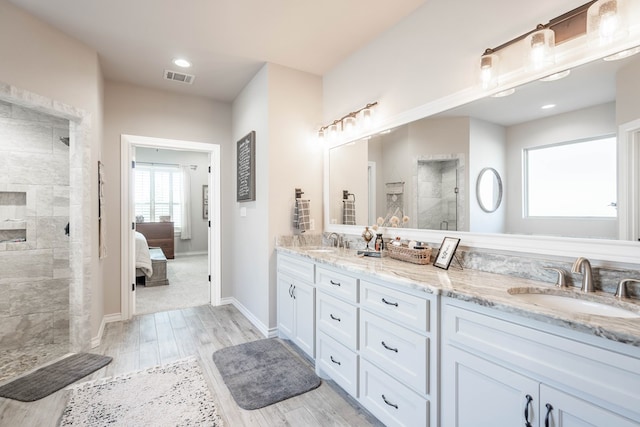 bathroom with a tile shower, hardwood / wood-style floors, and vanity