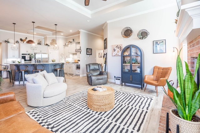 living room featuring ornamental molding, a tray ceiling, ceiling fan, and light hardwood / wood-style floors