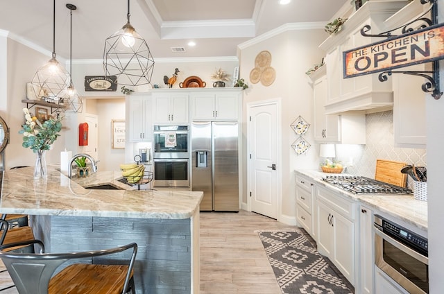 kitchen featuring sink, stainless steel appliances, light hardwood / wood-style floors, decorative light fixtures, and white cabinets