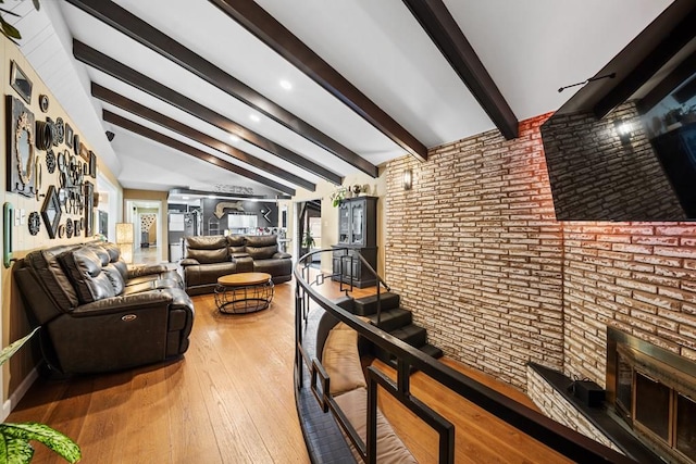 living room with vaulted ceiling with beams, wood-type flooring, and brick wall