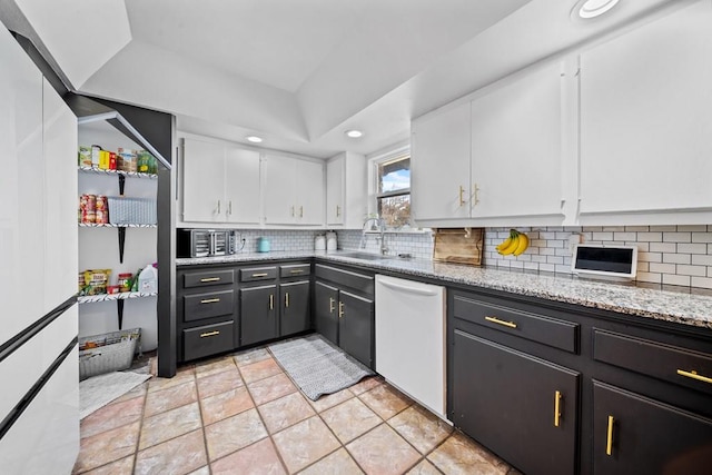 kitchen with white cabinetry, sink, light stone countertops, backsplash, and white dishwasher