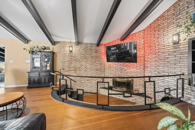 living room with hardwood / wood-style flooring, lofted ceiling with beams, and brick wall