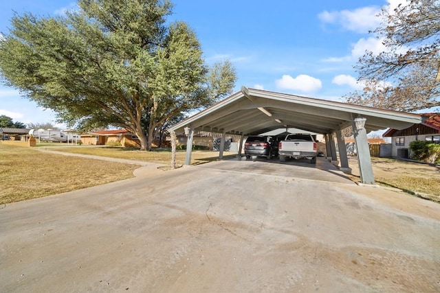 view of parking / parking lot featuring a carport and a lawn