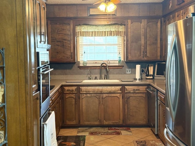 kitchen featuring ceiling fan, a sink, light countertops, appliances with stainless steel finishes, and a textured ceiling