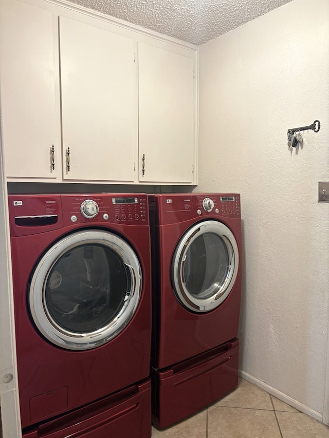 washroom with light tile patterned floors, cabinet space, a textured ceiling, and separate washer and dryer