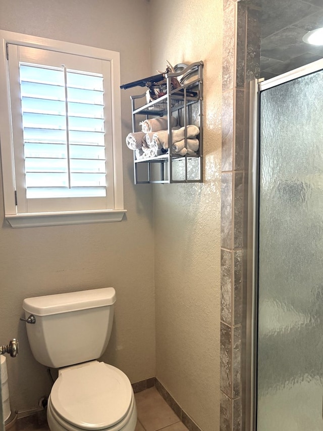 full bathroom featuring baseboards, toilet, a shower stall, and tile patterned flooring