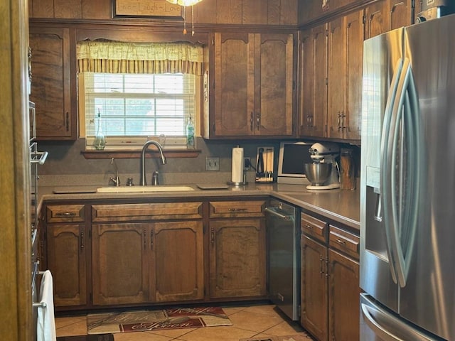 kitchen with light tile patterned floors, stainless steel refrigerator with ice dispenser, and a sink